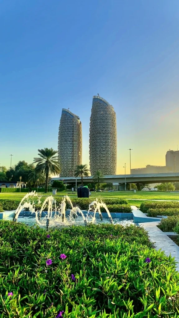 Modern twin towers surrounded by palm trees, green gardens and fountains in Dammam, Saudi Arabia